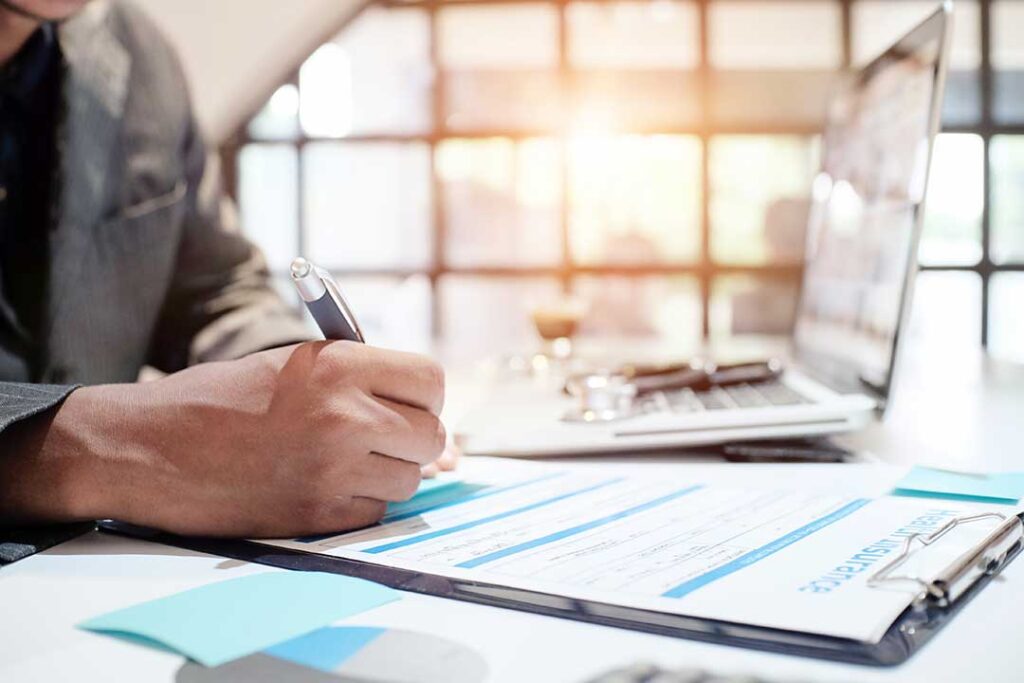 Patient reviewing surgery coverage documents with an insurance form and medical records on a desk.
